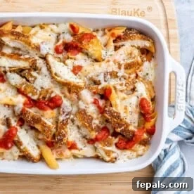 Ultimate Chicken Parm Bake 11 a baking white dish with pasta and tomato sauce topped with crispy chopped chicken and melted cheese.