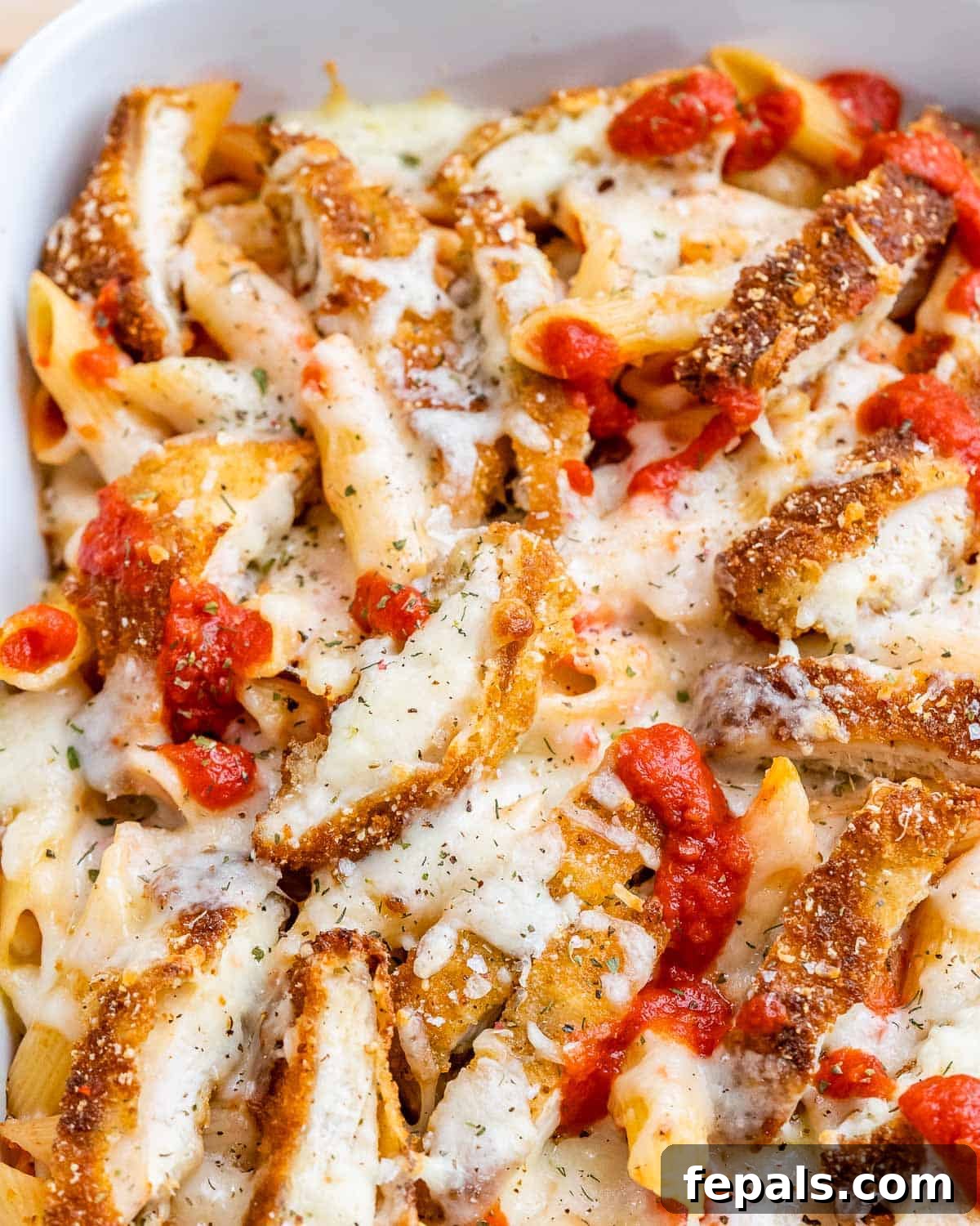Ultimate Chicken Parm Bake 8 Chicken parmesan casserole with melty cheese and marinara sauce served in a white baking dish.