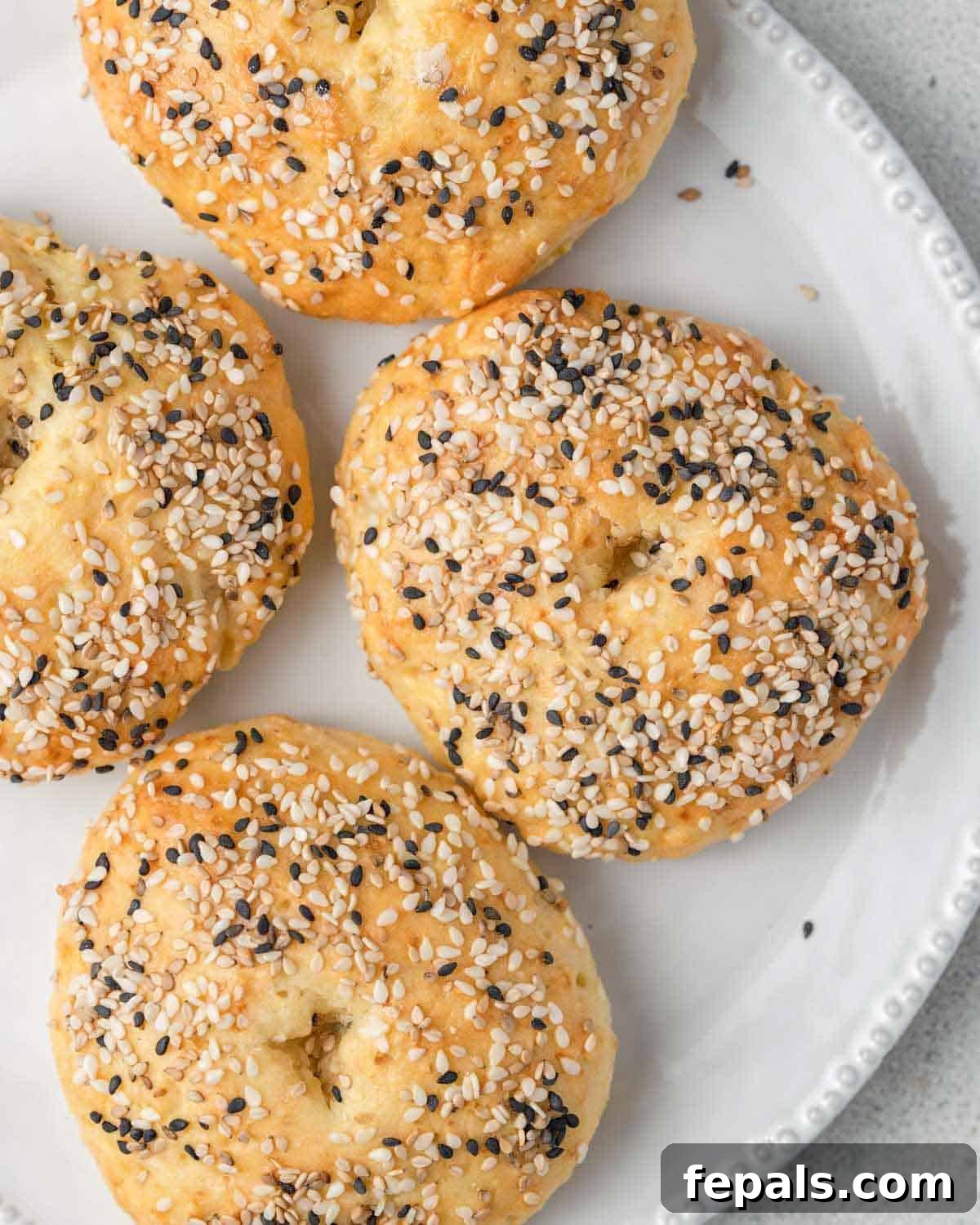 Protein Packed Cottage Cheese Bagels Yeast Free 2 Four golden-brown, freshly baked cottage cheese bagels arranged on a plate.