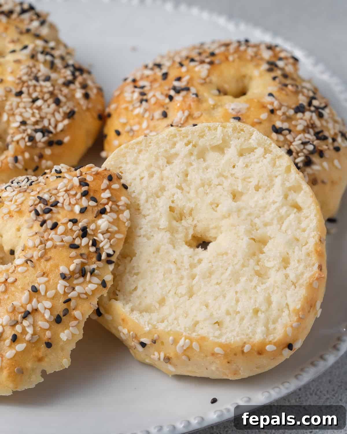 Protein Packed Cottage Cheese Bagels Yeast Free 9 A freshly baked cottage cheese bagel, perfectly sliced in half, revealing its tender interior, on a small plate.