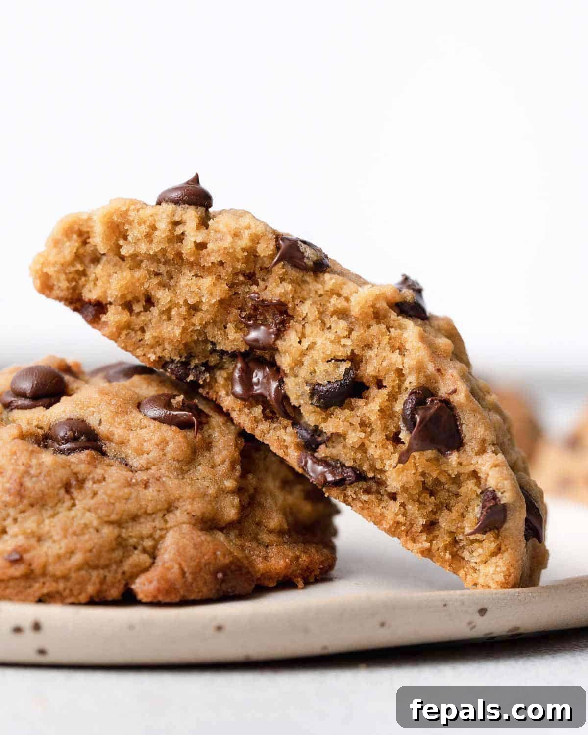 Liquid Gold Chocolate Chip Cookies 12 half a cookie sitting over another cookie on a plate.
