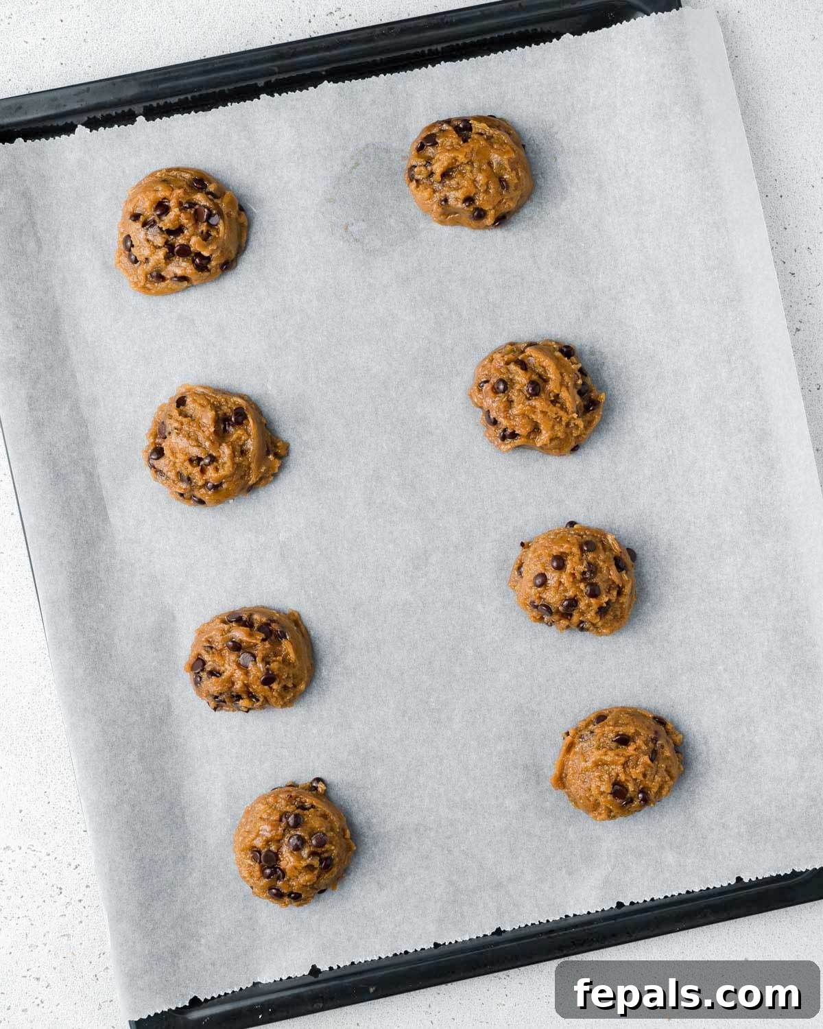 Liquid Gold Chocolate Chip Cookies 9 Dough balls on a parchment-lined cookie sheet.