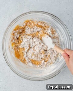 dry ingredients added over wet ingredients and being mixed in a bowl.