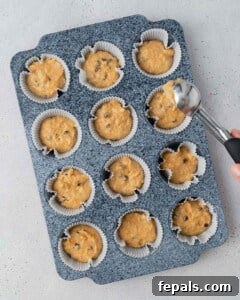 sweet potato muffin batter is added to a muffin pan.