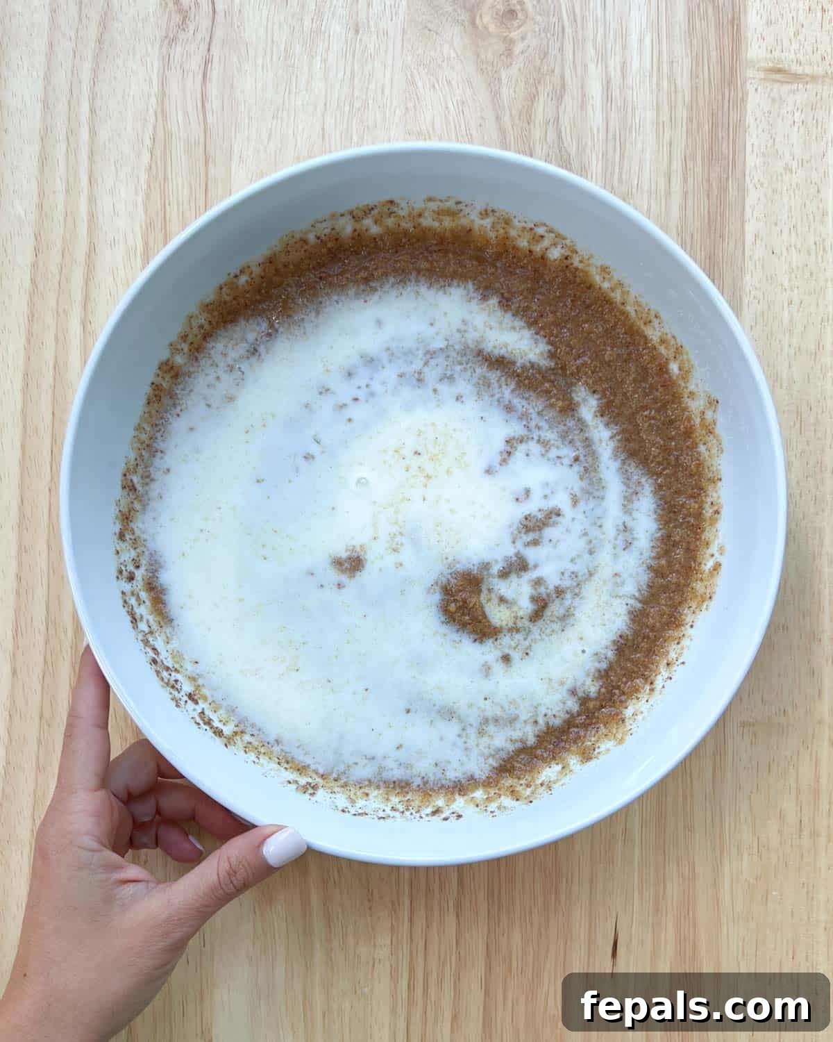 Cozy Apple Oat Squares 5 Almond milk being poured over the peanut butter mixture in a white mixing bowl.
