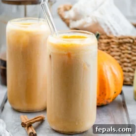 Two glasses of pumpkin latte with glass straws in them, topped with a sprinkle of spice, showcasing the rich color and inviting texture of the drink.