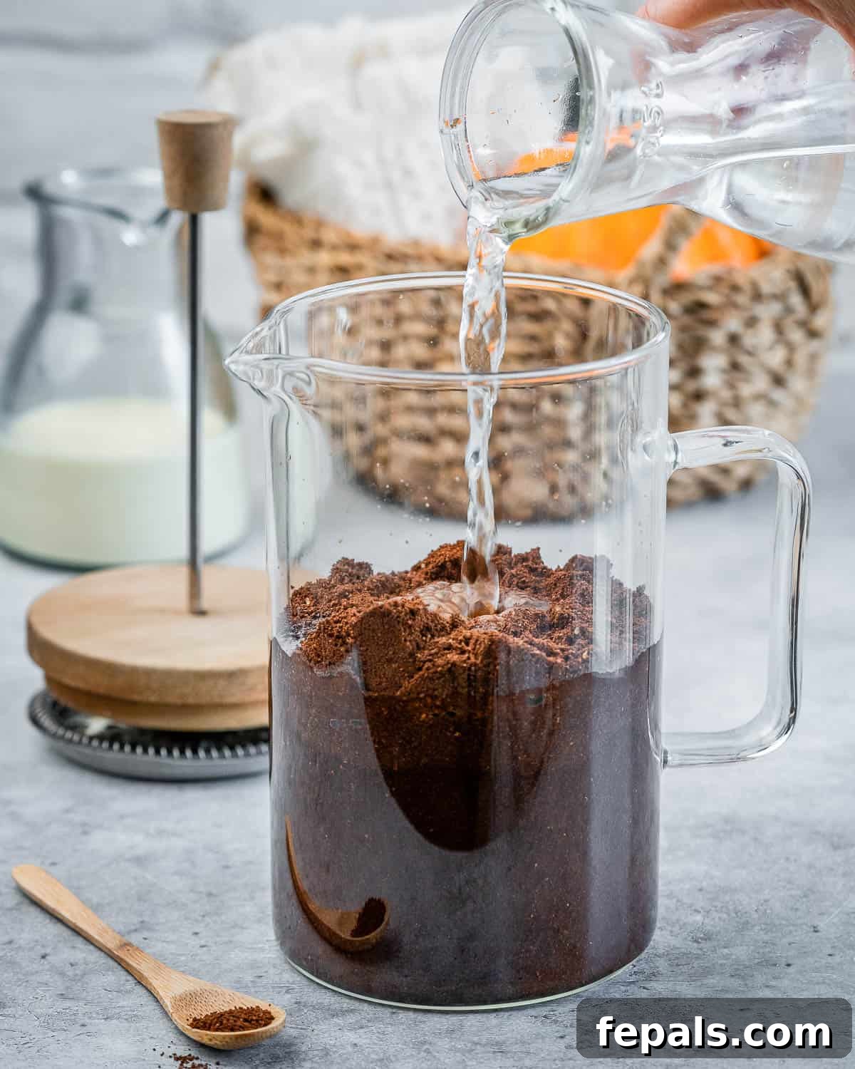 Step 1: Pouring cold water into a French press already containing coarsely ground coffee beans, initiating the cold brew process.