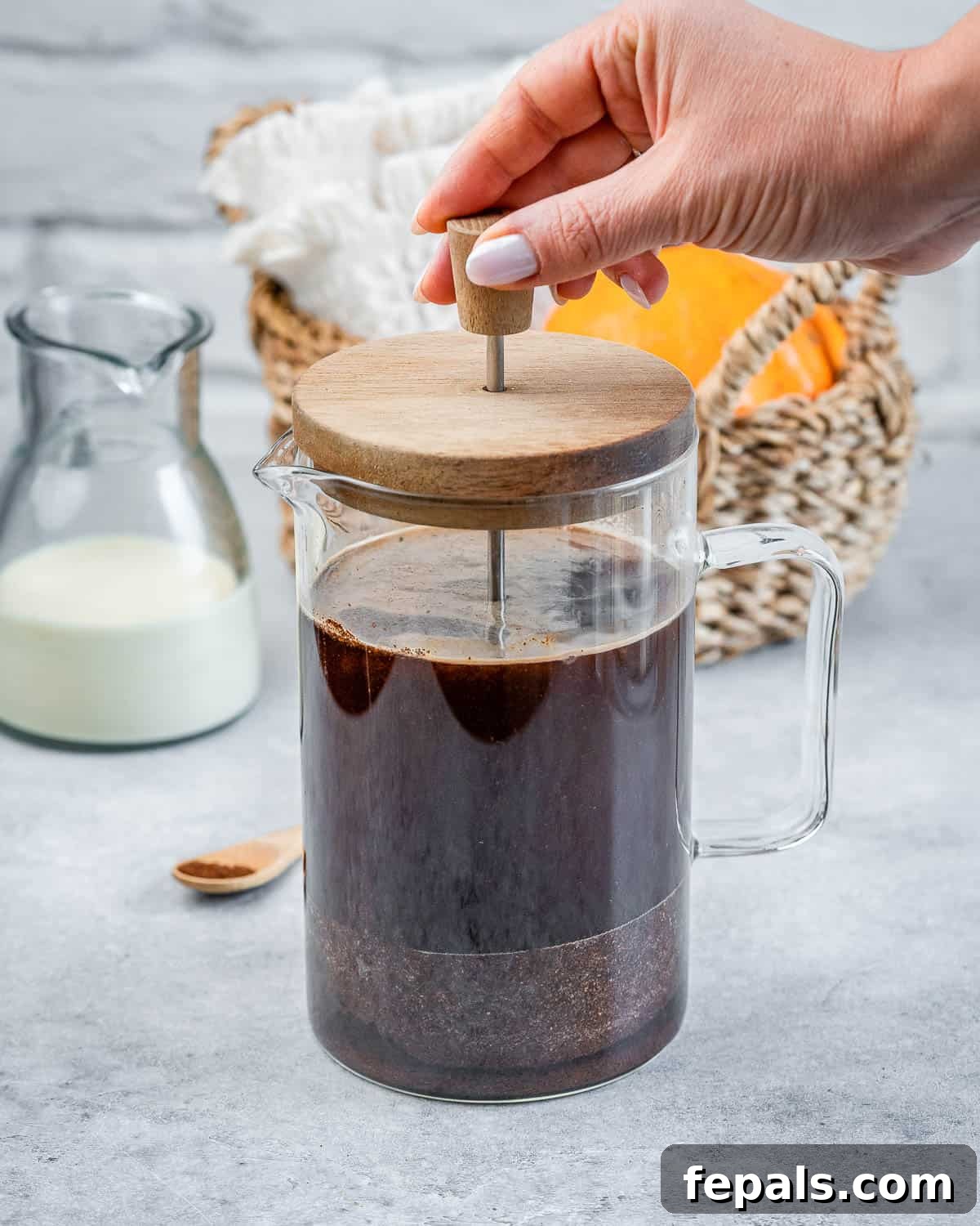 Step 2: Pressing down the plunger of a French press after overnight steeping, separating the coffee grounds from the rich cold brew concentrate into a pitcher.