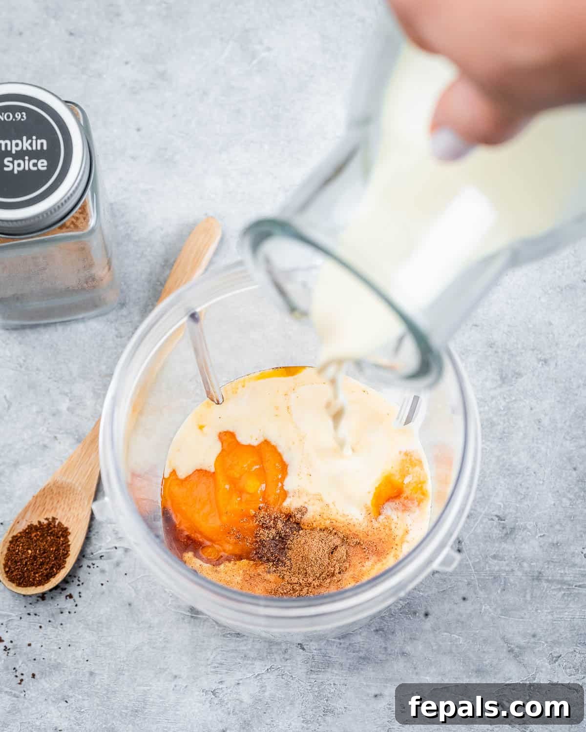 Step 3: Adding sweetened condensed milk, maple syrup, canned pumpkin puree, pumpkin pie spice, and vanilla extract into a blender jug, preparing for the pumpkin cream blend.