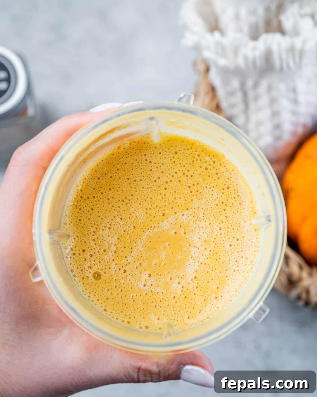 Step 4: Blending the pumpkin cream ingredients in a small handheld blender, creating a smooth and airy mixture with a beautiful orange hue.