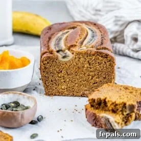 Pumpkin bread on a flat surface with two slices sliced off.