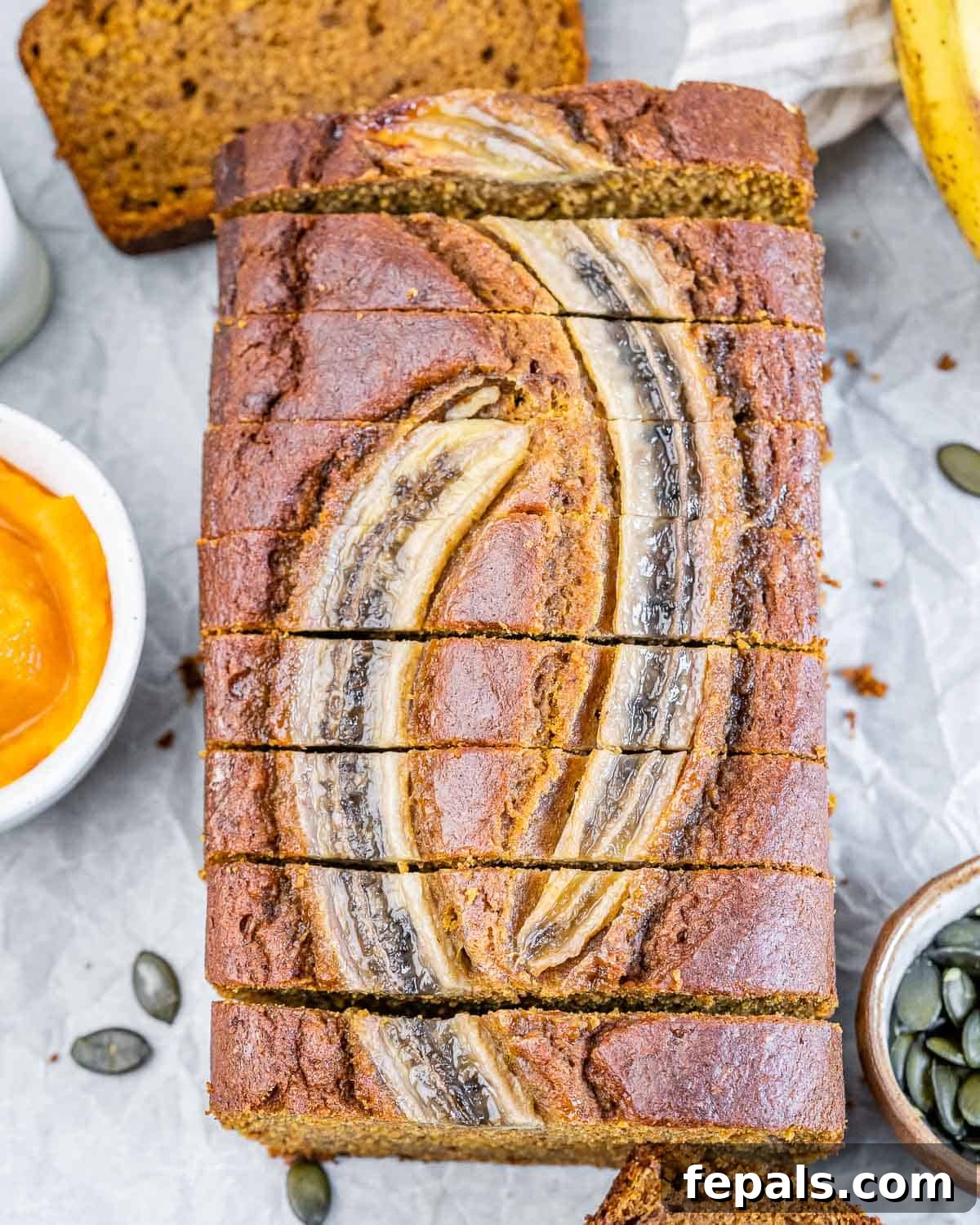 A freshly baked loaf of pumpkin banana bread, perfectly golden and sliced, revealing its moist and tender interior.