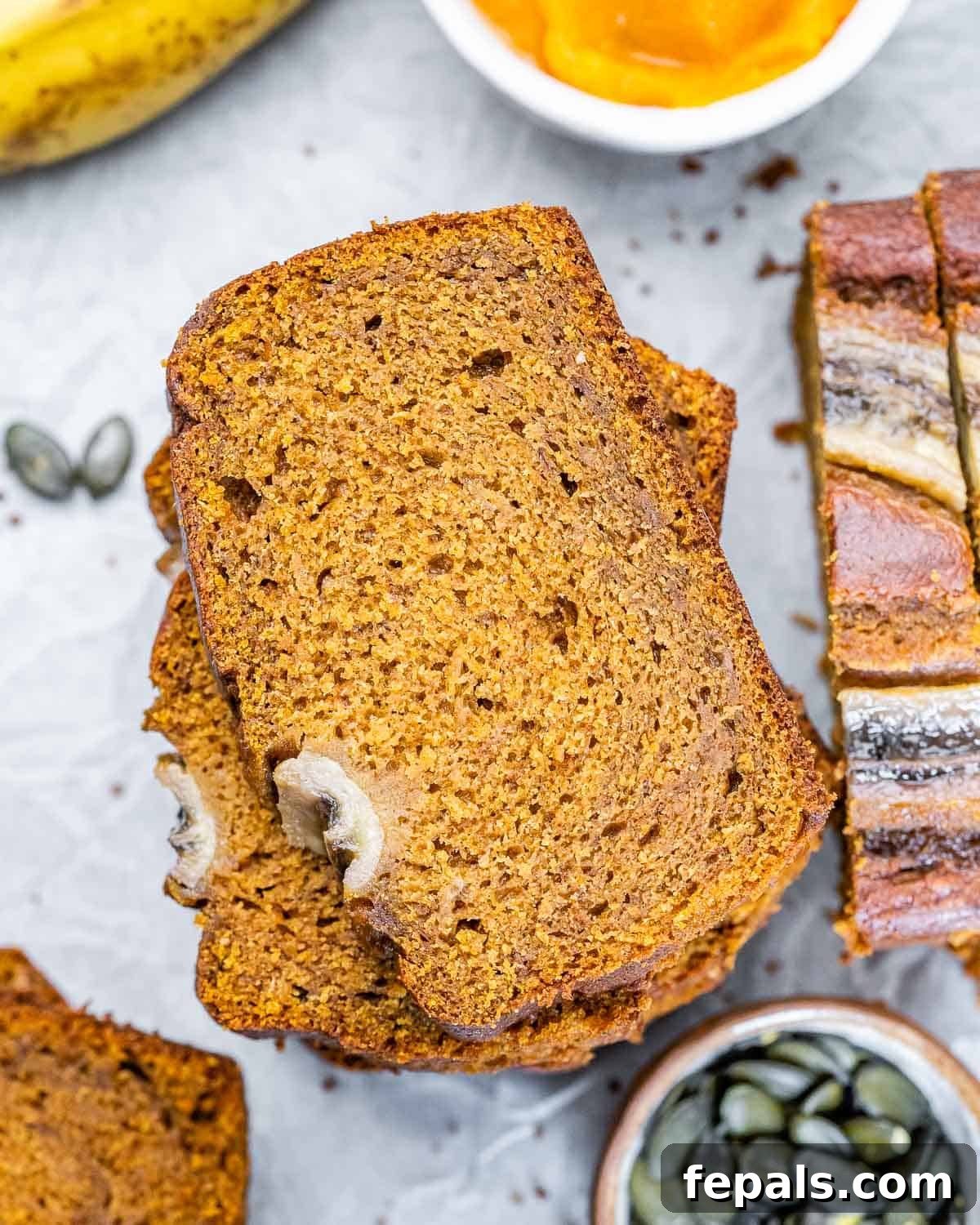 Multiple stacks of perfectly sliced pumpkin banana bread, showcasing the moist interior and appealing crust, ready to be served.