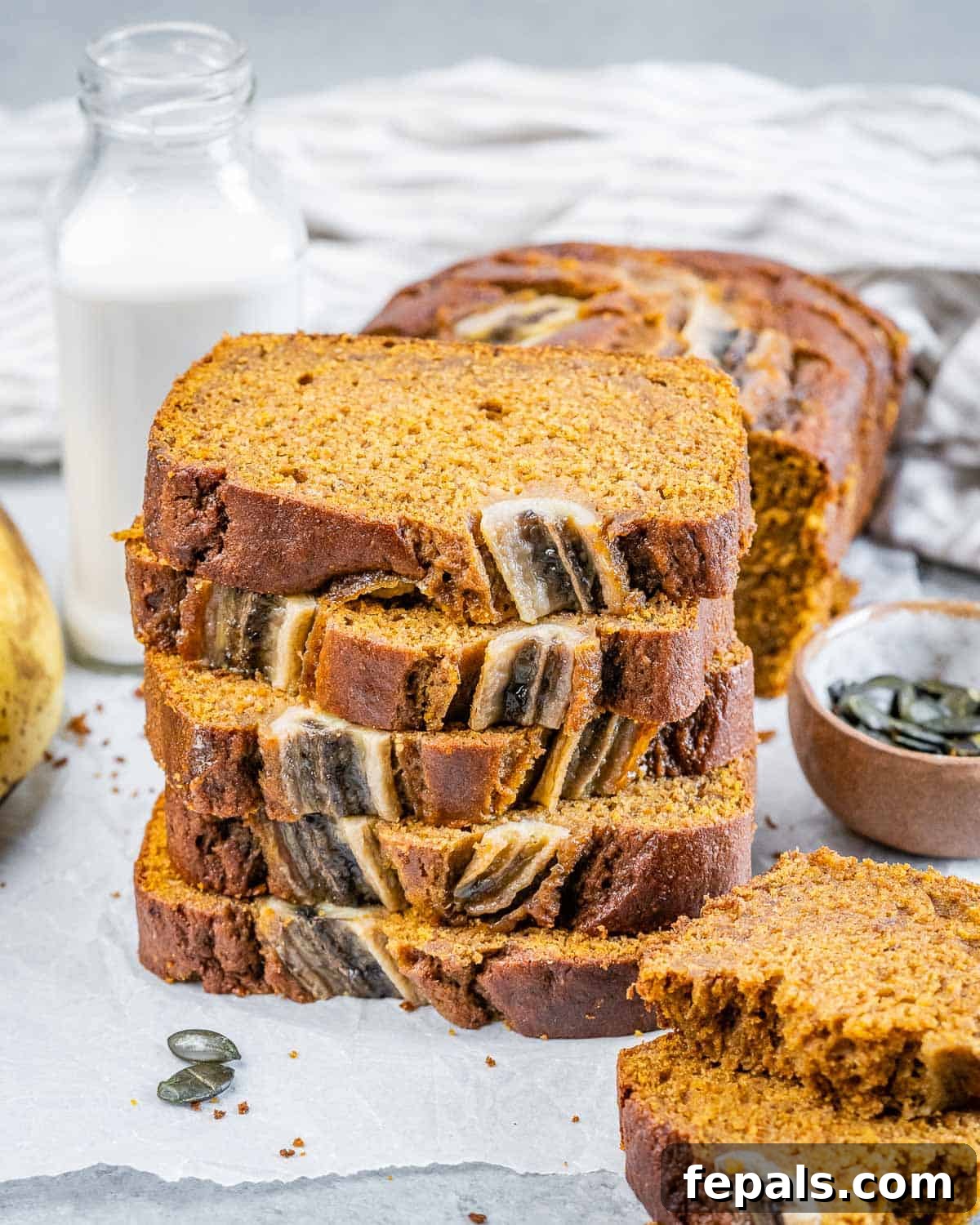 Neatly stacked slices of pumpkin banana bread, showcasing the golden crust and tender, spiced interior.