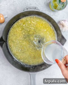 Starchy pasta water being poured into the skillet to loosen the lemon sauce.