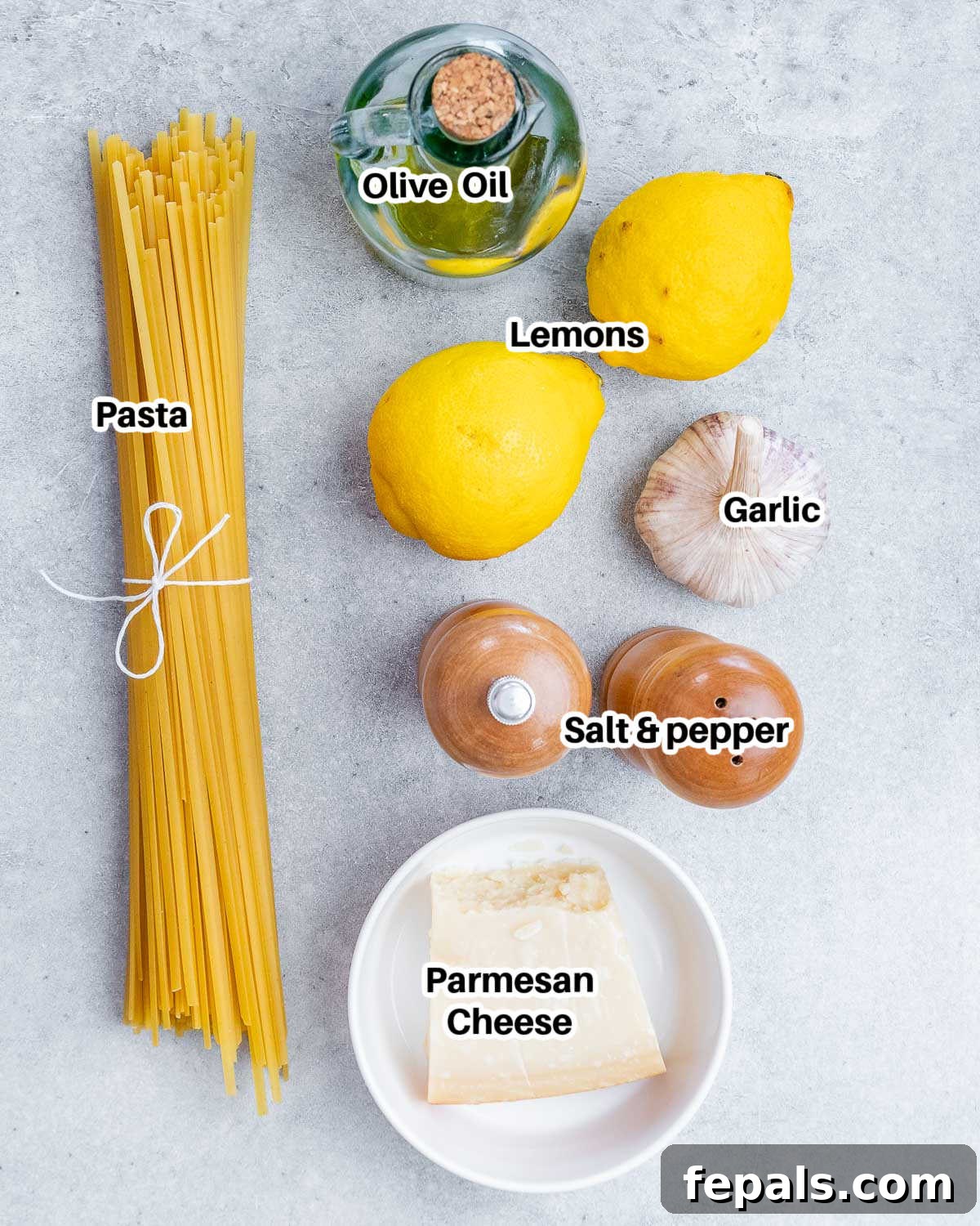 Collection of fresh ingredients for Pasta al Limone: pasta, lemons, garlic, olive oil, and Parmesan cheese.
