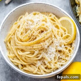 lemon linguine pasta in a white bowl topped with shaved parmesan.