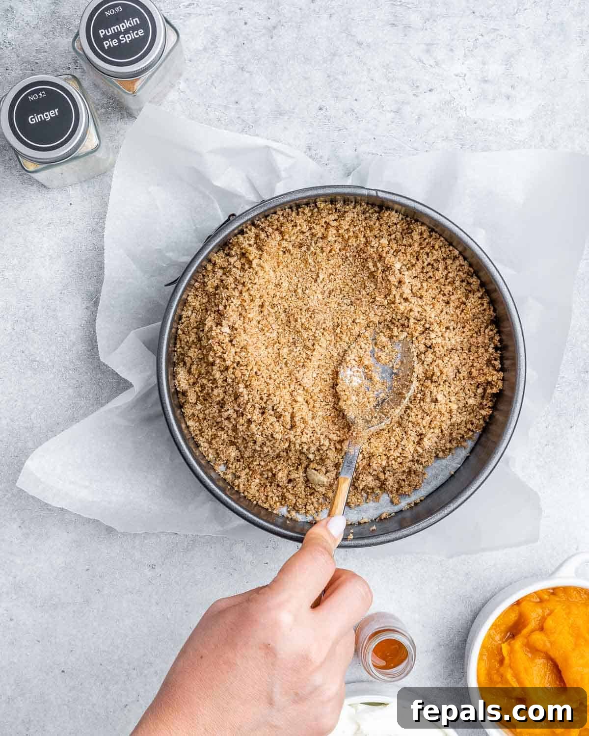 Pressing crumbled crackers into the bottom of a pan.