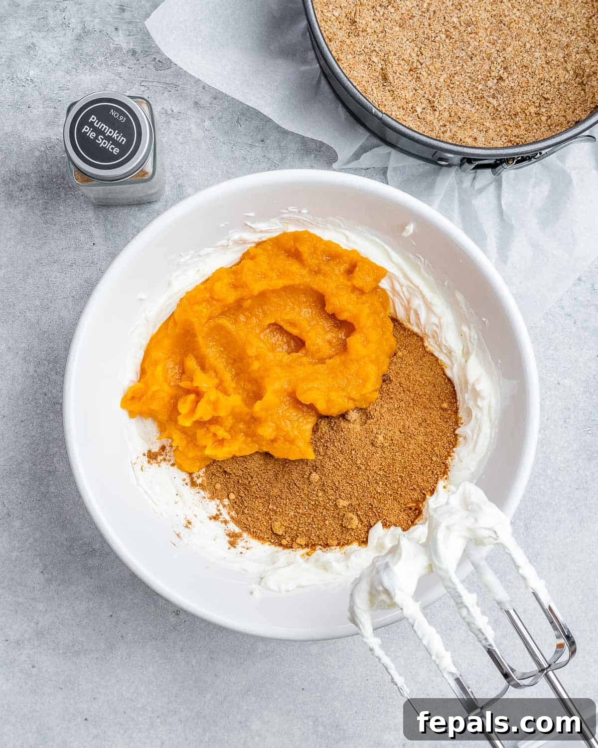 Adding sugar and pumpkin puree to whipped cream cheese.