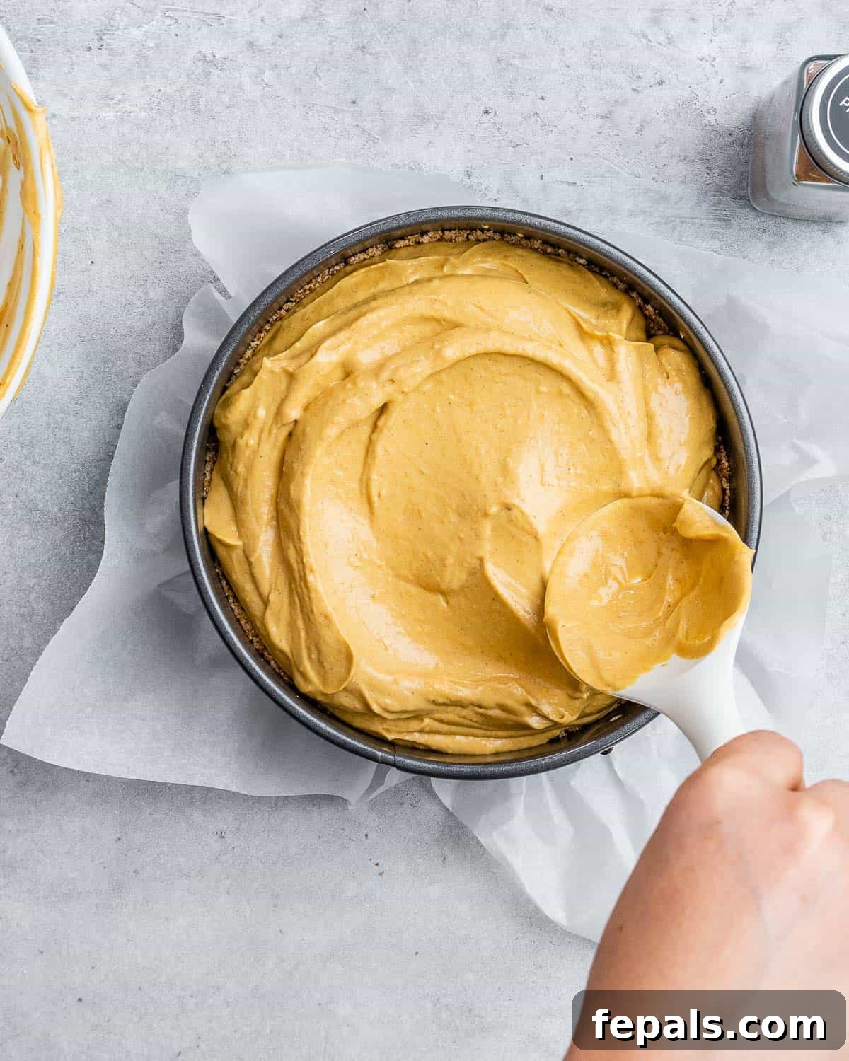 Spreading pumpkin cheesecake filling into a springform pan.