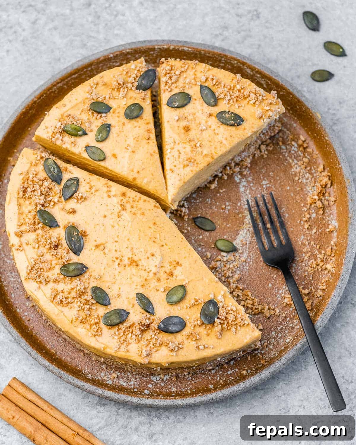 Pumpkin cheesecake with slices cut off it and fork on the plate.
