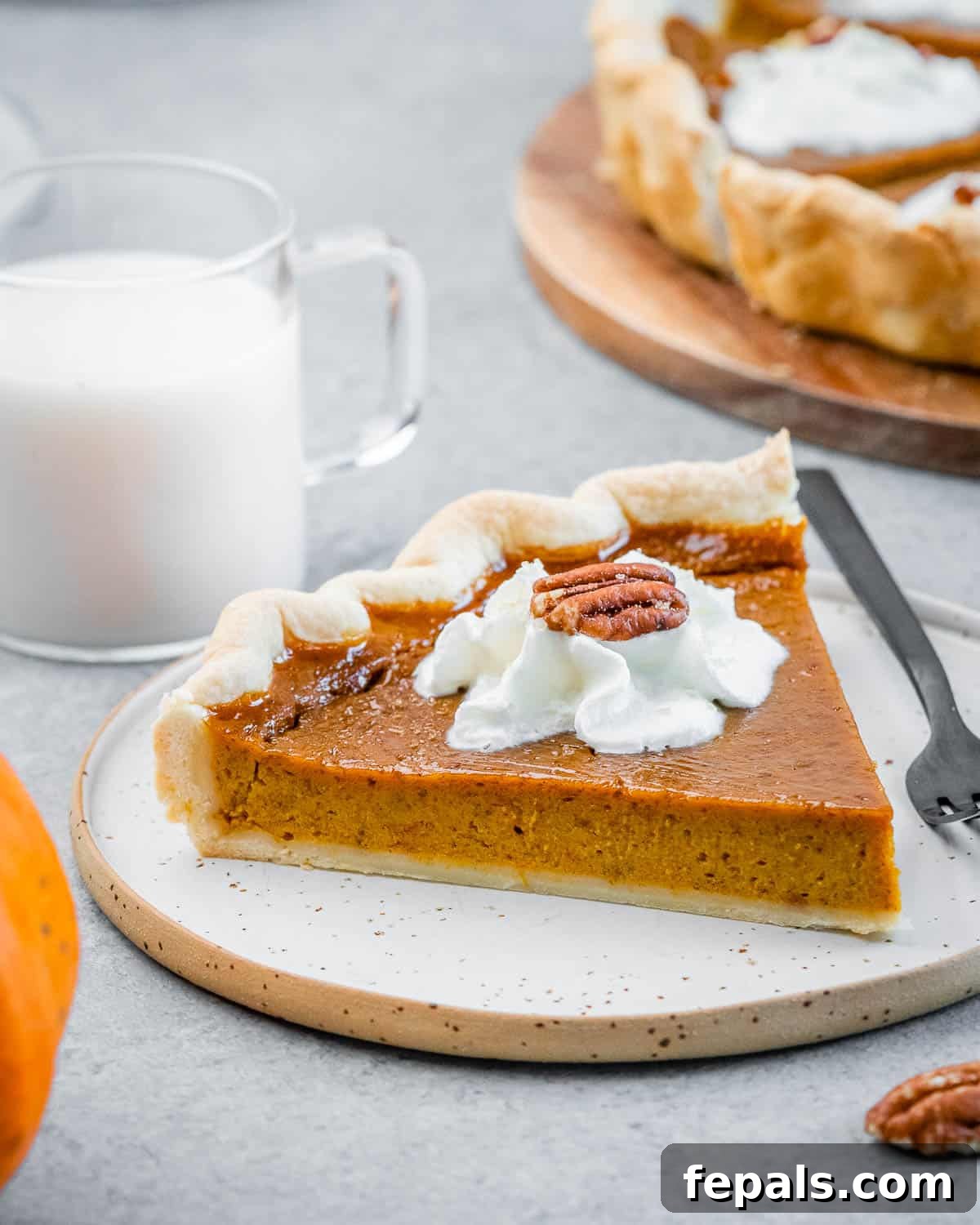 Wholesome Pumpkin Pie 2 A beautifully sliced healthy pumpkin pie on a white plate, ready to be enjoyed with a fork beside it.