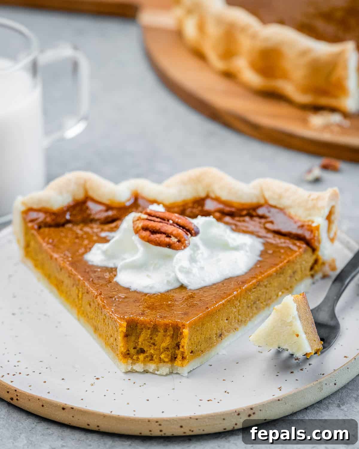 Wholesome Pumpkin Pie 8 A delectable slice of healthy pumpkin pie on a white plate, with a fork having just taken a bite, showing the creamy texture.