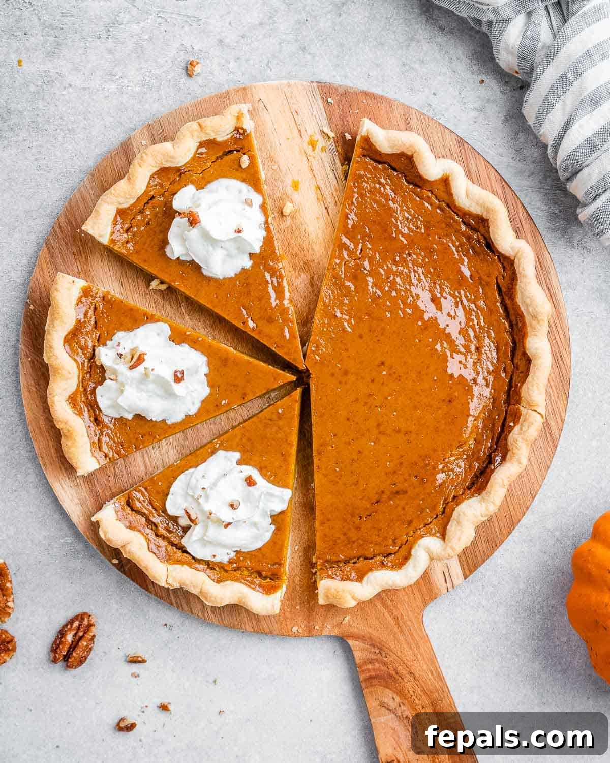 Wholesome Pumpkin Pie 9 A beautifully baked healthy pumpkin pie, sliced, with dollops of fluffy whipped cream on each slice, ready for serving.