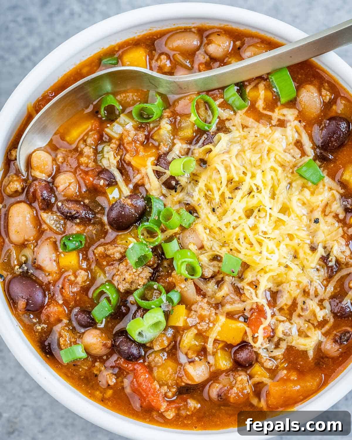 Easy Crockpot Chili 2 Hearty Crockpot Chili topped with fresh green onions and shredded cheddar cheese, ready to serve.