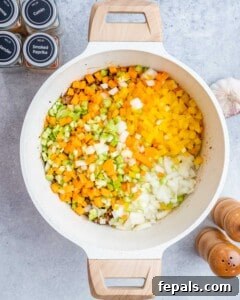Easy Crockpot Chili 13 Adding veggies to browned beef in a pot.