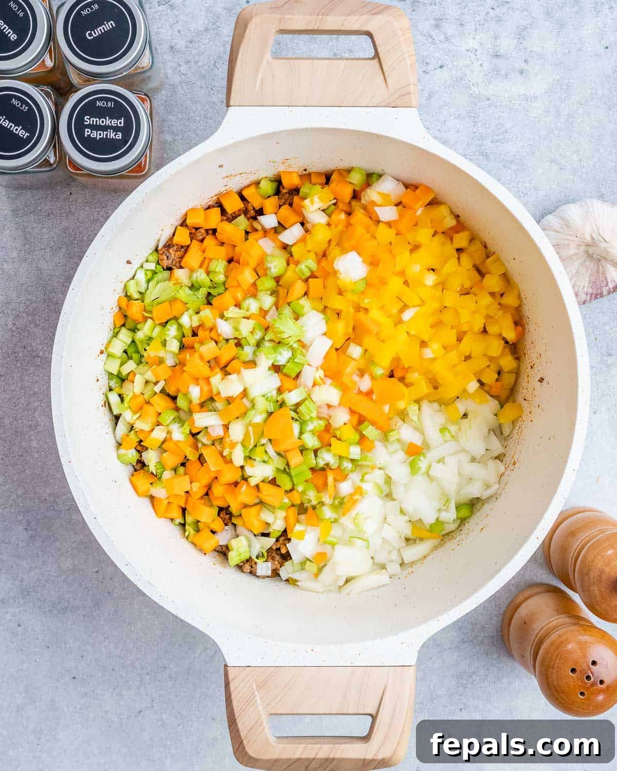 Easy Crockpot Chili 5 Adding diced carrots, celery, bell pepper, onion, and minced garlic to browned beef in a pot.