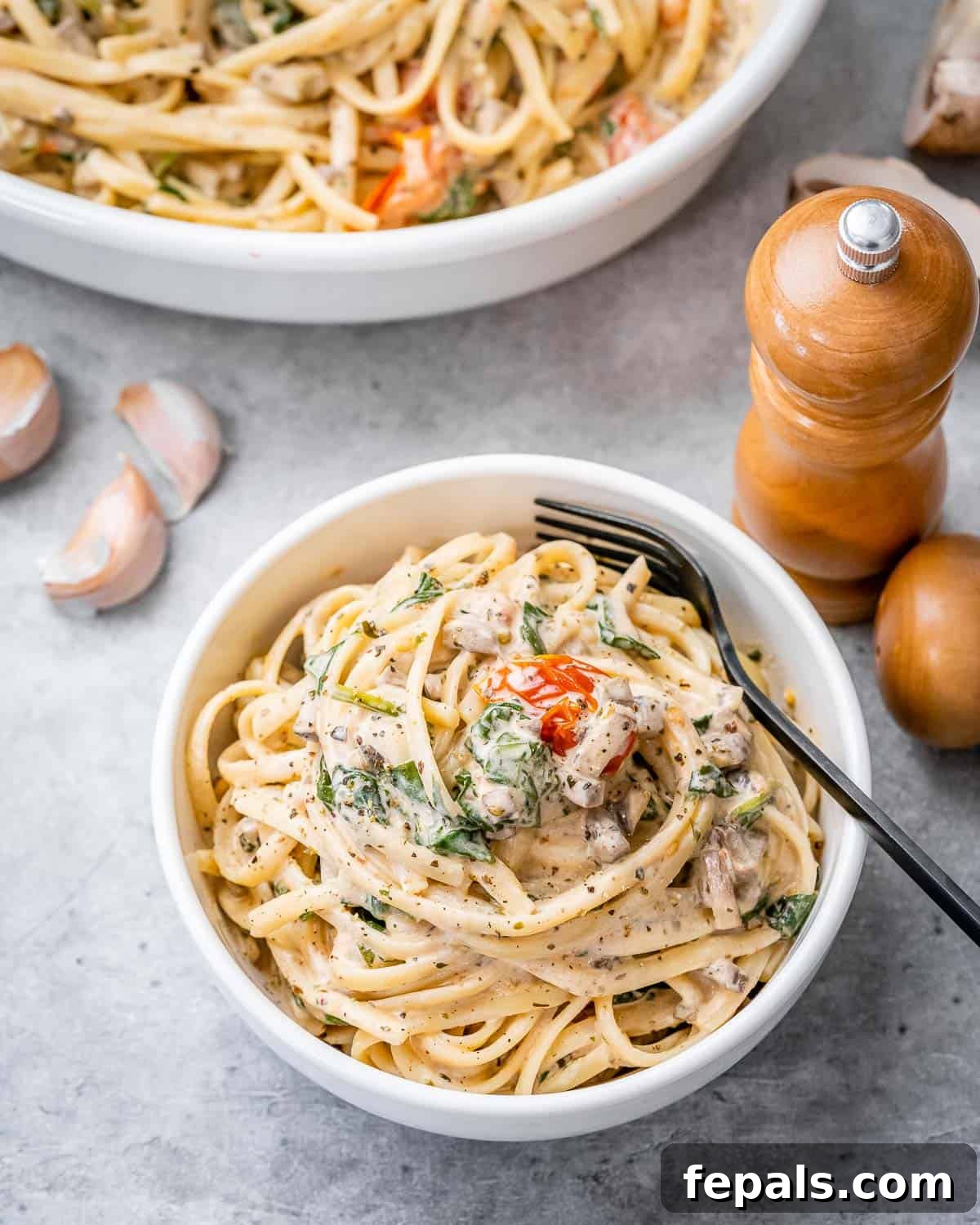 Blush Tomato Cream Pasta 12 A perfectly cooked creamy spaghetti in a round white bowl with a fork, ready to be enjoyed.