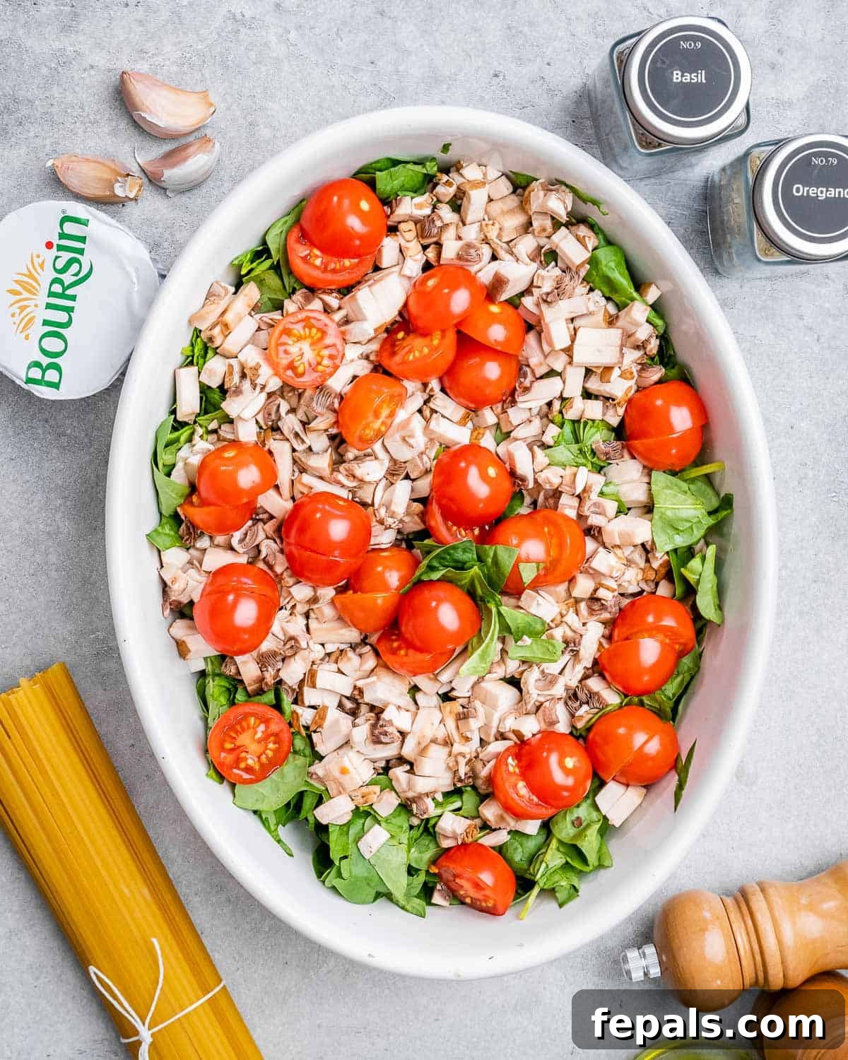 Blush Tomato Cream Pasta 4 Spinach, cherry tomatoes, chopped mushrooms, and garlic cloves in a large baking dish, drizzled with olive oil and seasoned with herbs.