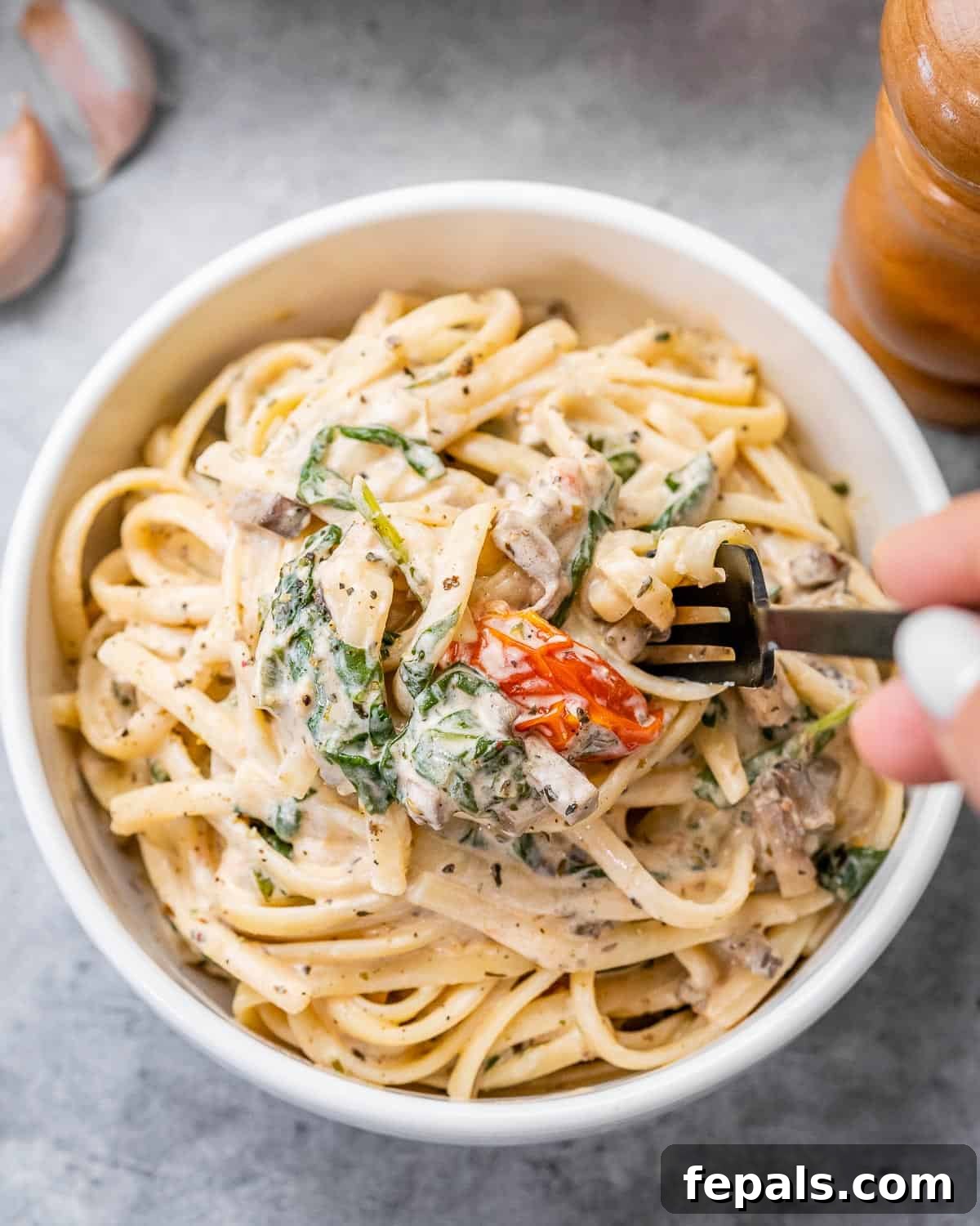 Blush Tomato Cream Pasta 10 A fork taking a bite of creamy tomato pasta bake from a round white bowl, showing the rich texture.