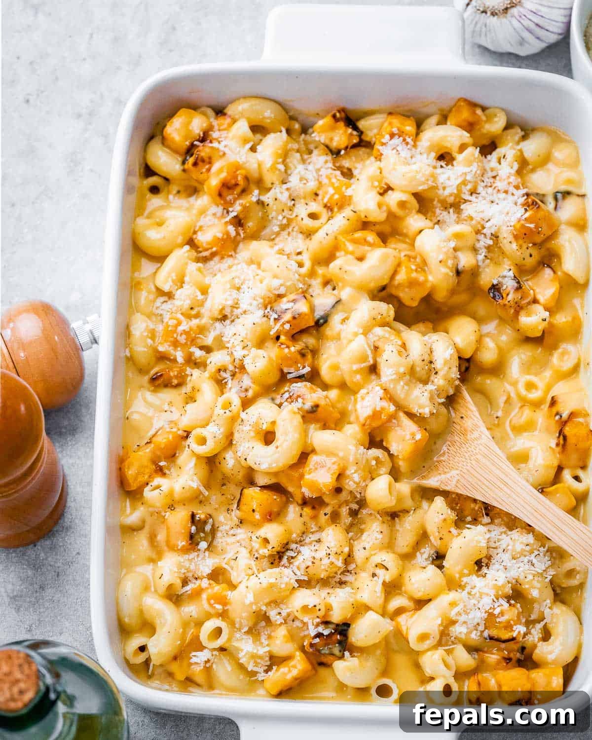 Velvety Butternut Mac and Cheese 2 A white dish with mac and cheese made with added roasted butternut squash, garnished with fresh herbs.