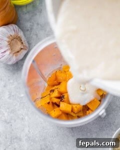 Velvety Butternut Mac and Cheese 7 Pouring milk into a blender with roasted butternut squash.