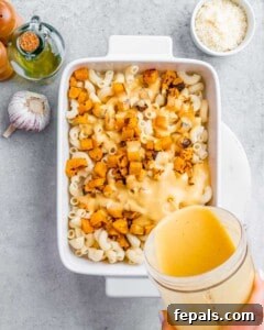 Velvety Butternut Mac and Cheese 8 Pouring sauce over macaroni noodles in a white baking dish.