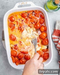 Smoked Tomato Bisque 17 Fork mashing the cheese and tomatoes in a baking dish.