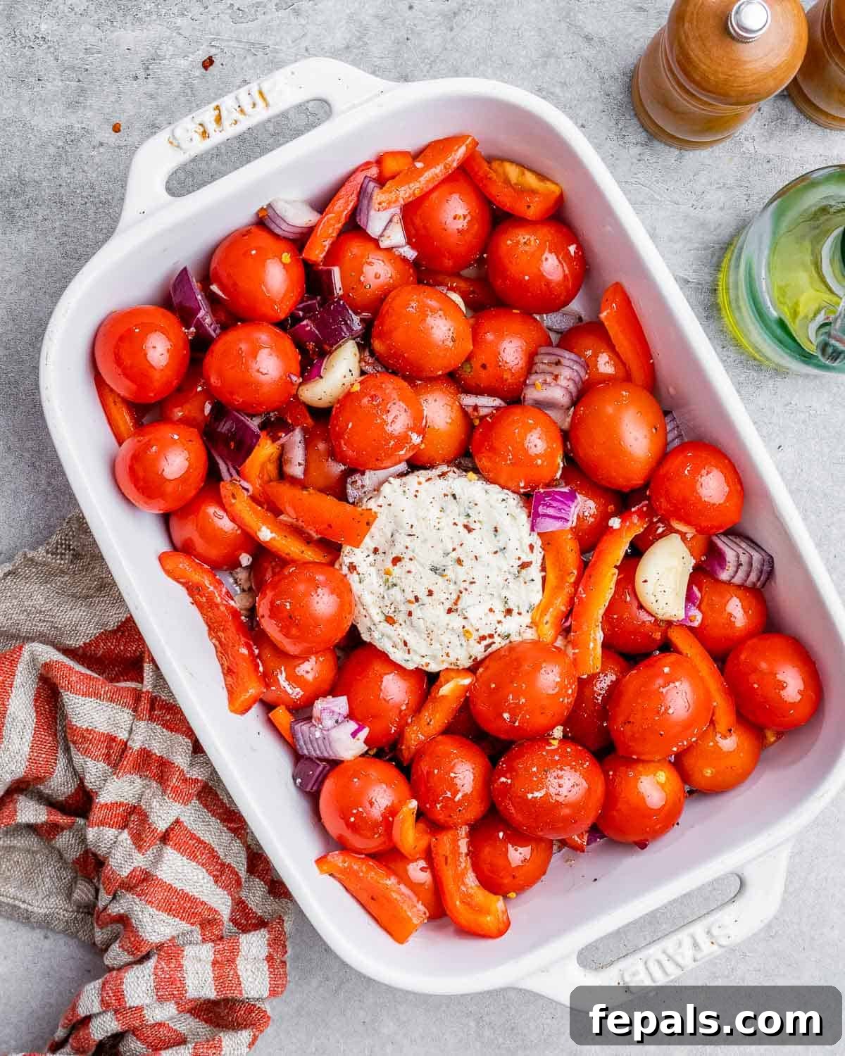Smoked Tomato Bisque 6 A block of Boursin cheese nestled in the center of the seasoned tomatoes, onions, and peppers in a white baking dish.