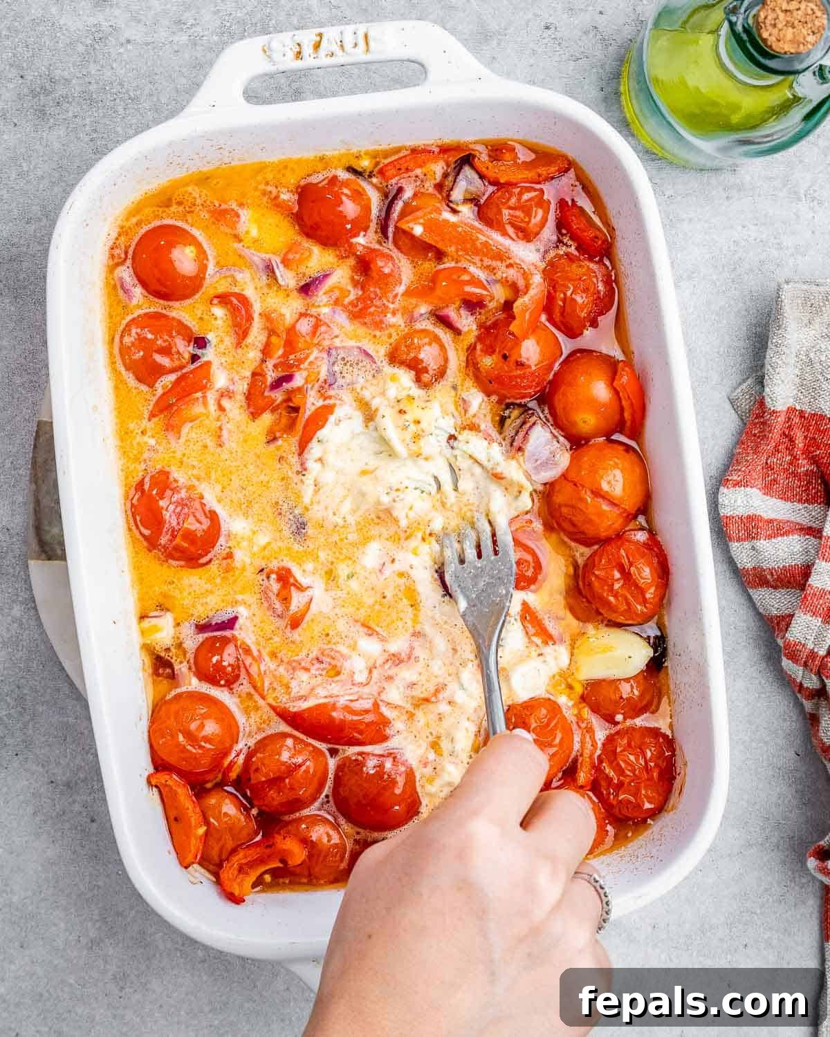 Smoked Tomato Bisque 8 A fork mashing together the soft roasted tomatoes, onions, peppers, and melted Boursin cheese in a baking dish.