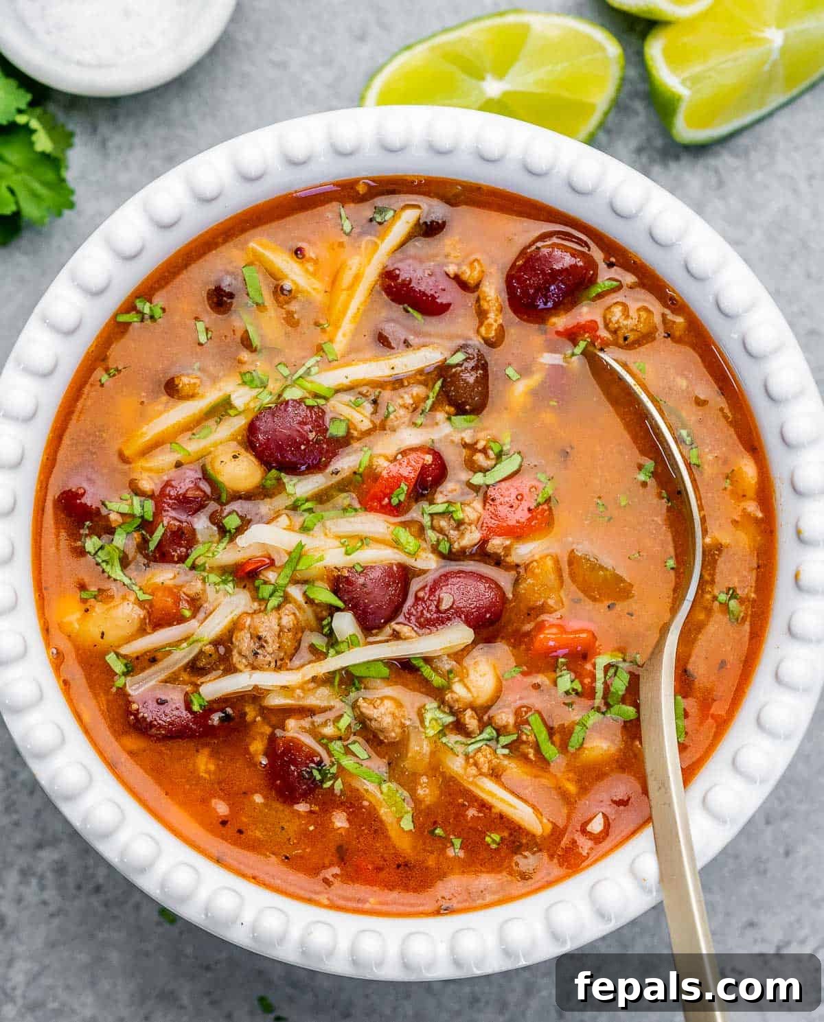 A white bowl of chili with spoon in the bowl.