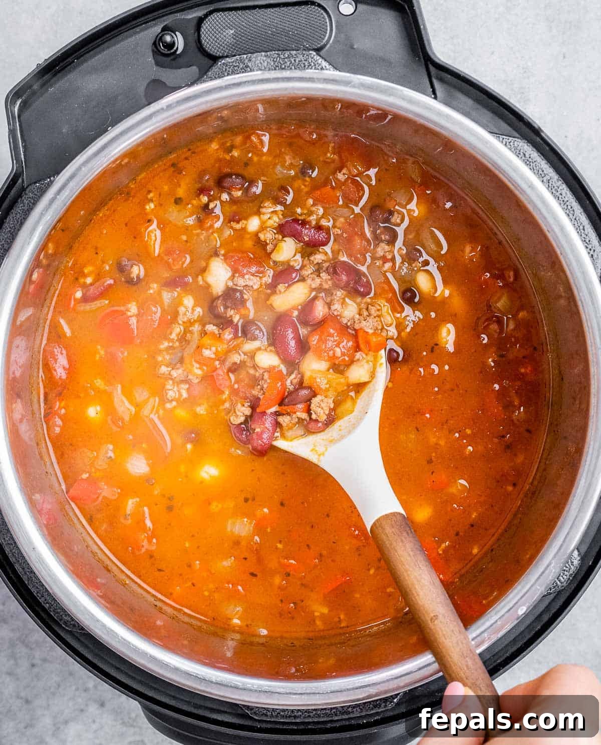 A white spatula stirring a pot of chili.