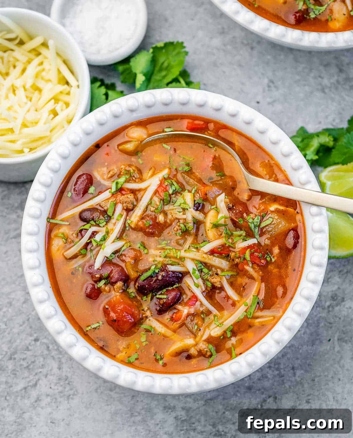 A white bowl of chili with spoon in the bowl.