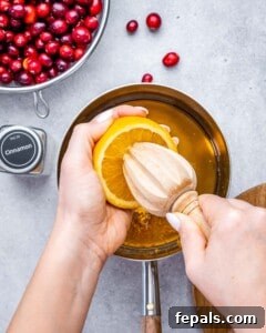 Squeezing fresh orange juice into a saucepan with maple syrup and orange zest.