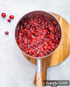 Cranberry orange sauce cooking in a saucepan.