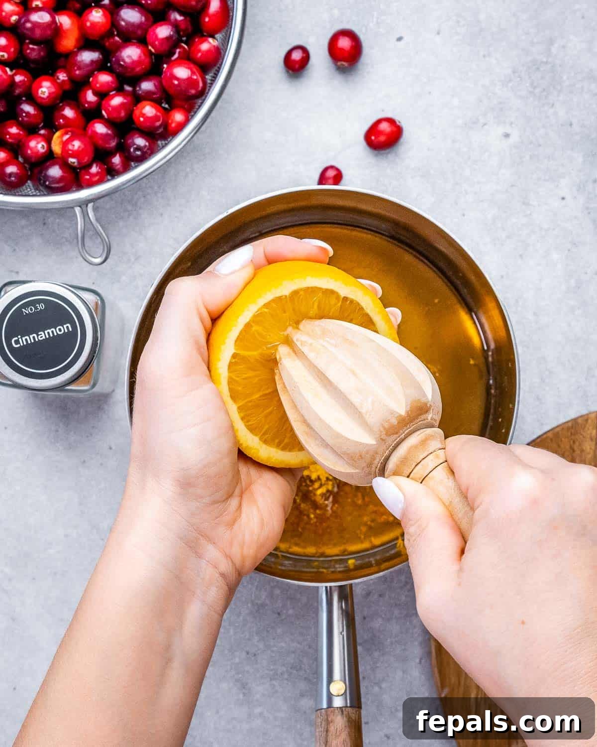 Vibrant Cranberry Orange Relish 3 Preparing cranberry sauce: Freshly squeezed orange juice, maple syrup, orange zest, and cinnamon are combined in a saucepan.