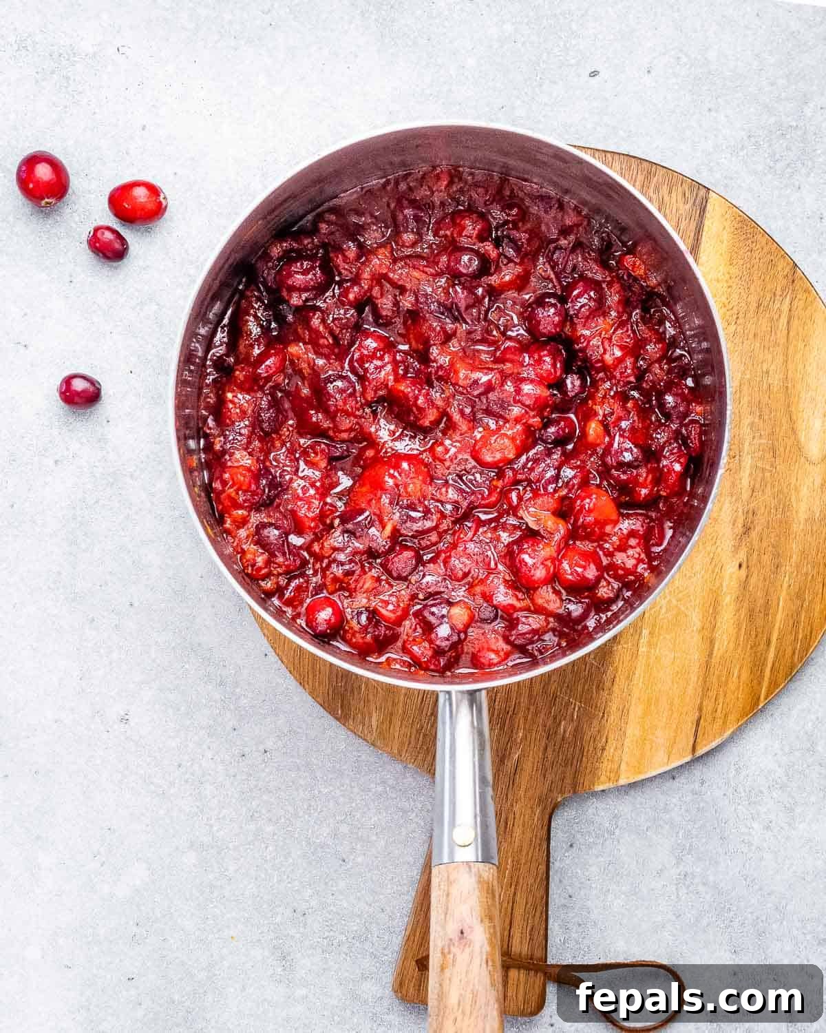 Vibrant Cranberry Orange Relish 5 Thickening process: The cranberry orange sauce simmering in a saucepan, with cranberries bursting and the sauce visibly thickening.