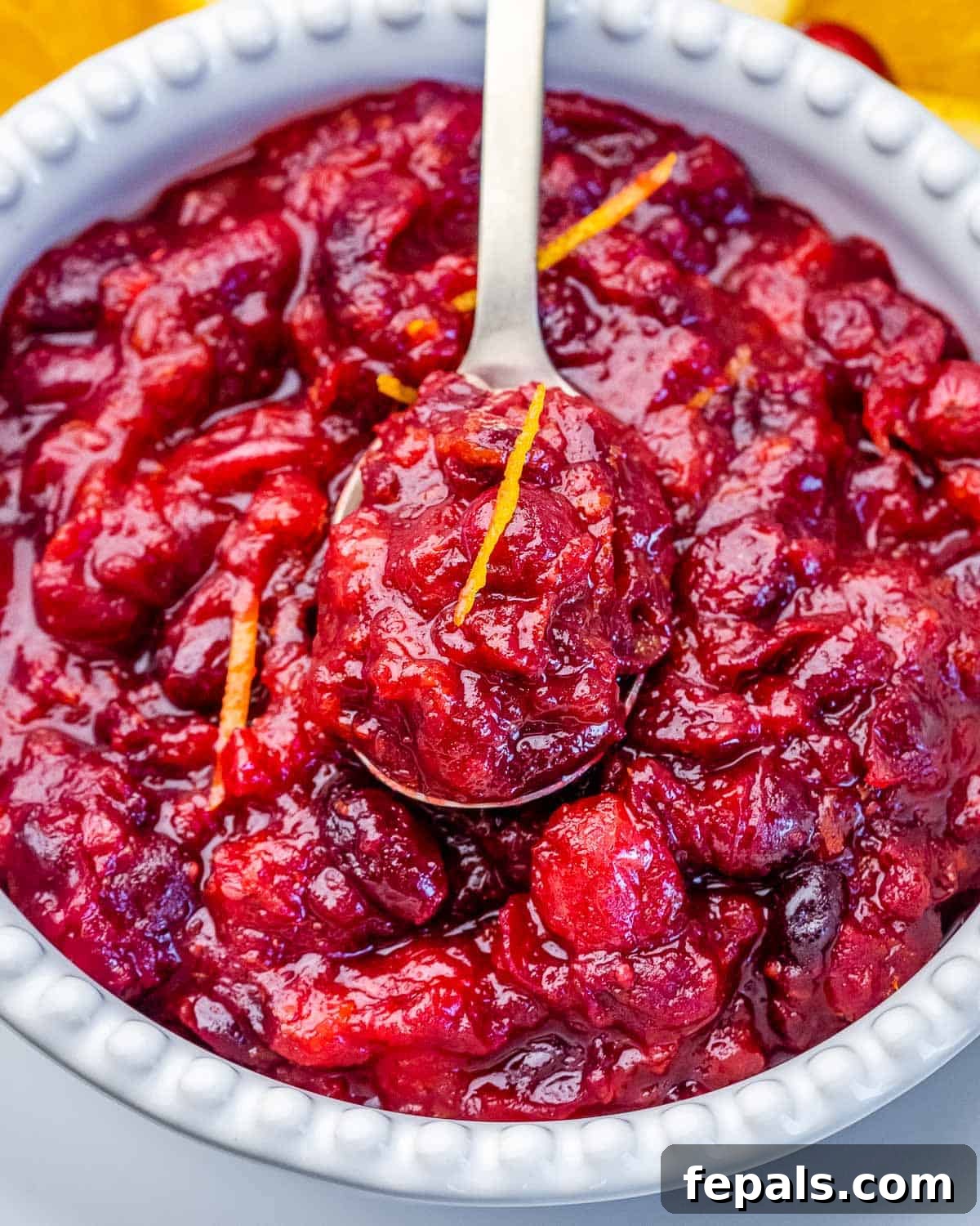 Vibrant Cranberry Orange Relish 6 Cooling the sauce: A spoonful of homemade cranberry orange sauce in a bowl, showing its rich texture after cooking, ready to cool and further thicken.