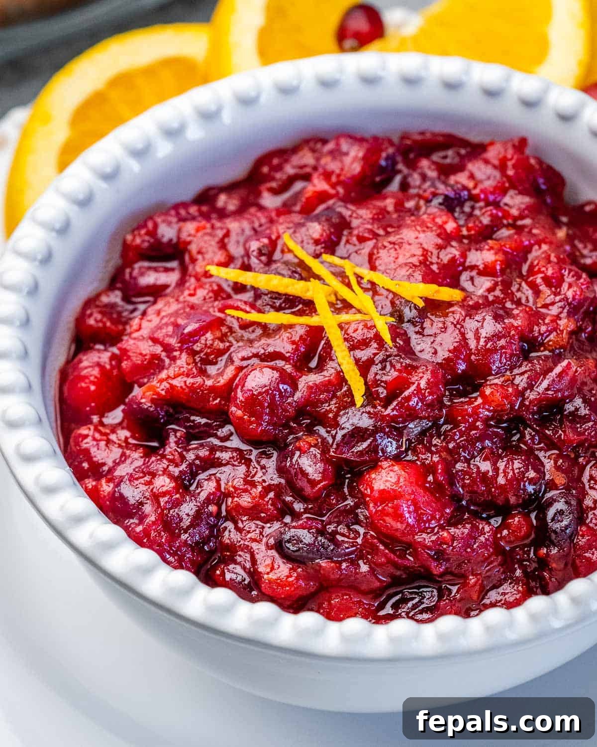 Vibrant Cranberry Orange Relish 7 A glistening bowl of homemade Cranberry Orange Sauce, beautifully garnished with delicate orange peel twists, ready to be a festive centerpiece.