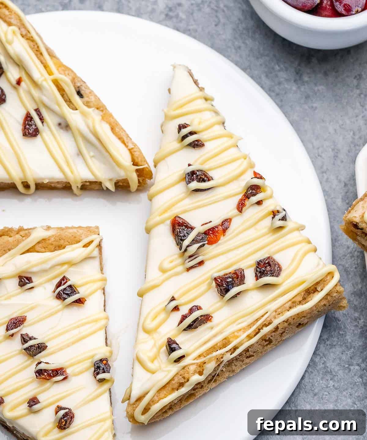 Three perfectly sliced cranberry bliss bars arranged on a white plate, showcasing their inviting layers.